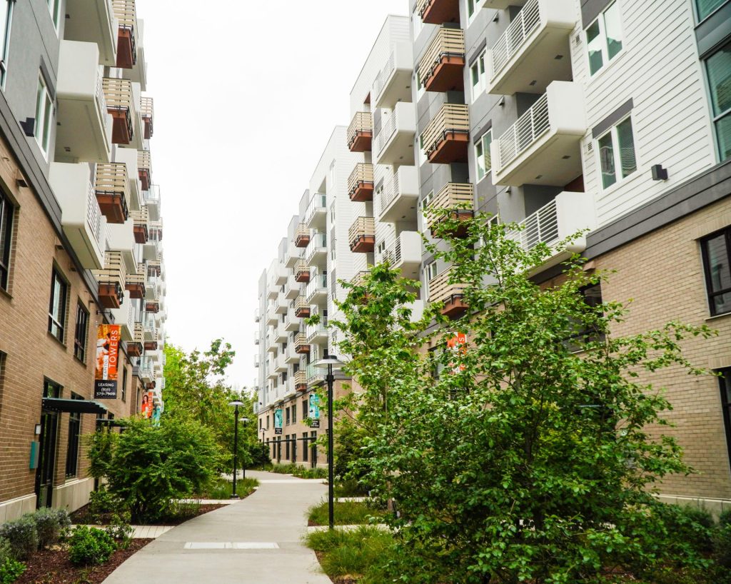 a sidewalk between two buildings with balconies