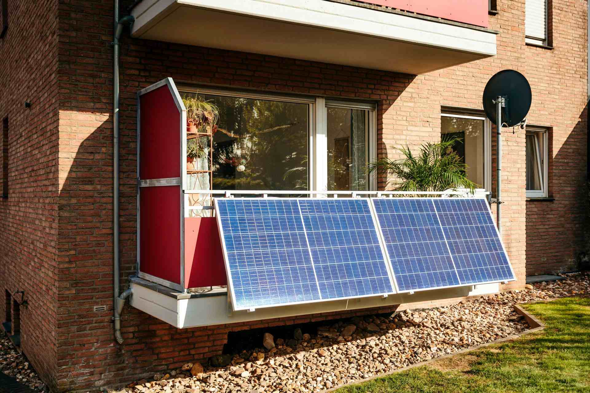 Panneaux solaires sur le balcon d'un immeuble en briques.