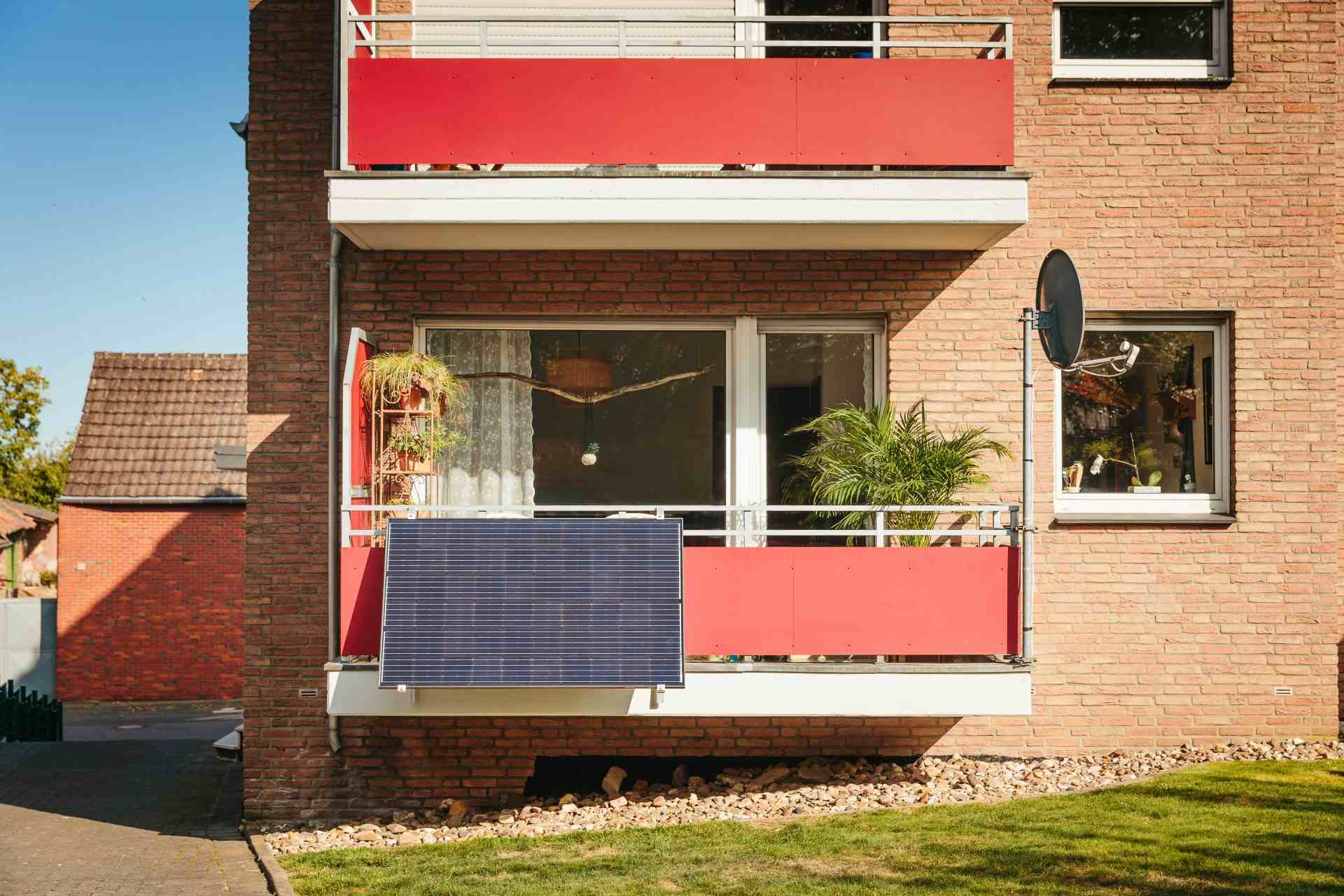 des écrans de balcon rouges sur un immeuble d'appartements en briques